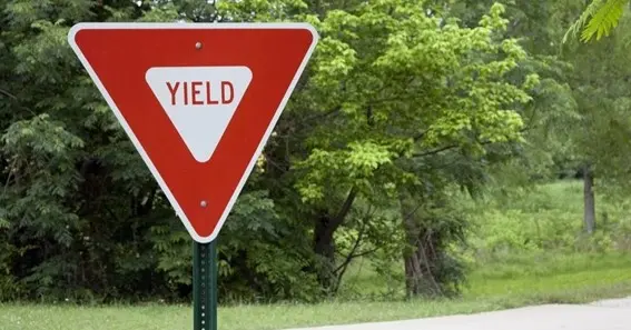 a red and white triangular sign at an intersection means